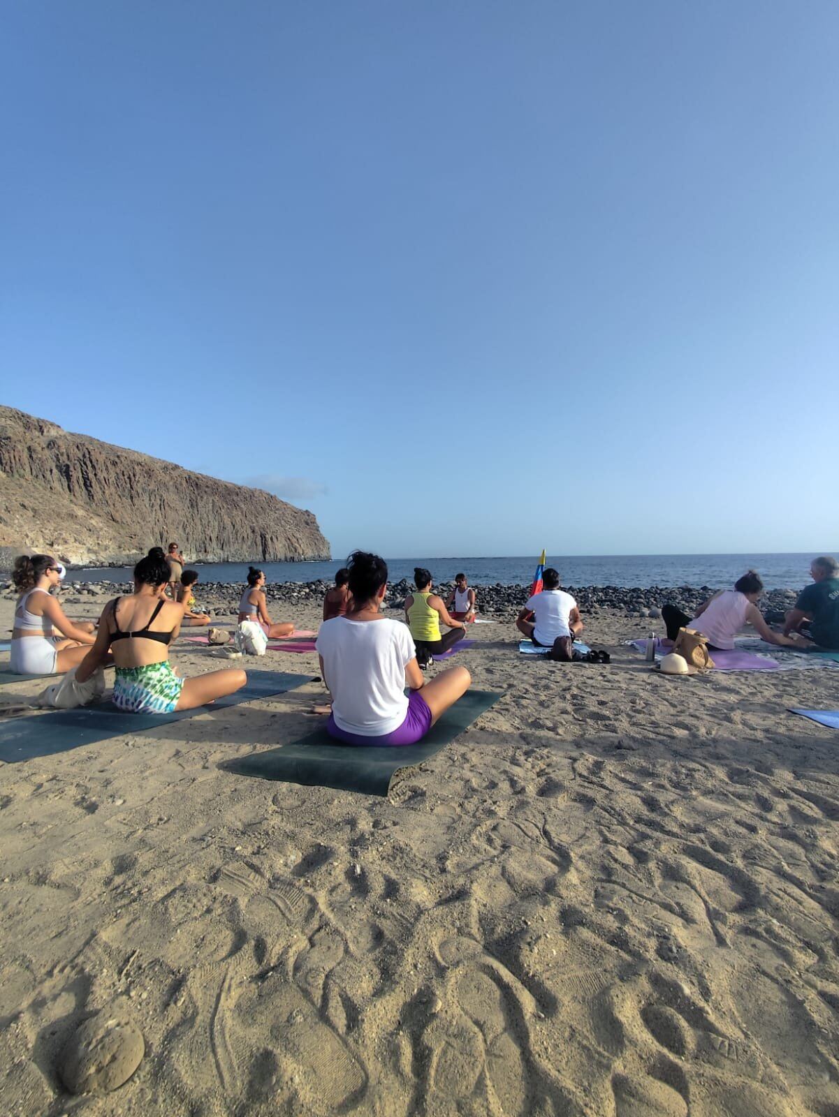 Alumnos sentados en meditación mirando al océano